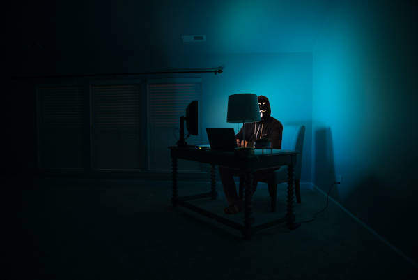 Een hacker achter zijn computer in een donkere kamer